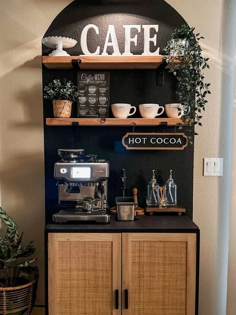 A coffee bar station with an espresso machine, wooden shelves, and a black arched wall alcove.
