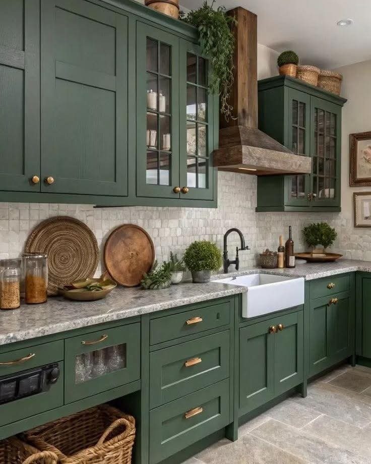 Dark green kitchen cabinets with gold handles, marble countertops, and a white farmhouse sink.