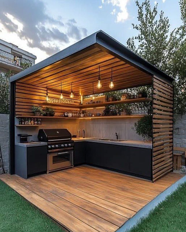 Modern outdoor kitchen with a black grill and wooden cabinetry under a slatted pergola.