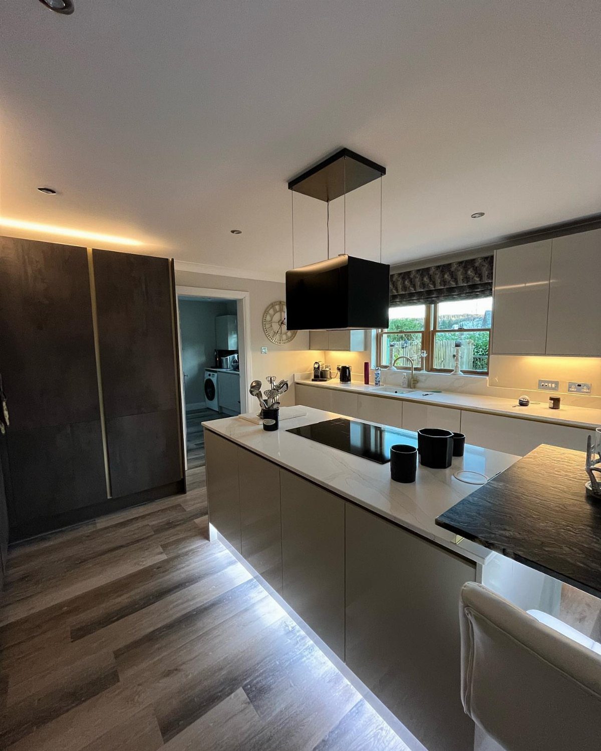 A modern kitchen island with a dark cooktop and integrated under-counter lighting.